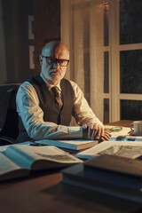 Confident professor sitting at desk and posing