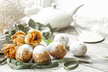 Cozy easter composition with eggs and flowers on wooden surface close up.