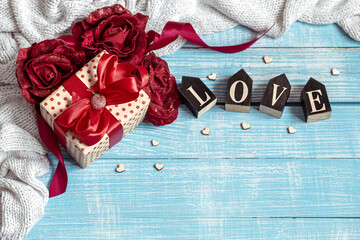 Festive composition for Valentine's Day with a gift box, knitted element and decorative word love.