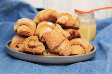 Homemade pastry. The rugelach with apple jam and condensed milk in a gray plate on a table. Traditional Jewish holiday cookie, Bagels, Croissants, Still life on blue textile background