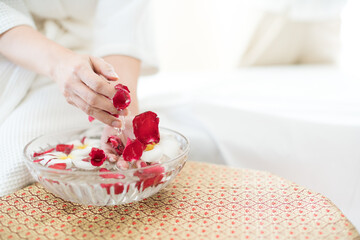 Woman washing hands with flower perfume in spa. woman holding essential water and fresh flowers.