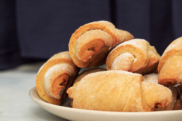 Homemade pastry. The rugelach with apple jam in a plate on a table. Traditional Jewish holiday cookie, Bagels, Croissants, Still life with dark background