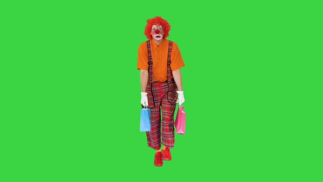 Tired clown with shopping bags walking on a Green Screen, Chroma Key.
