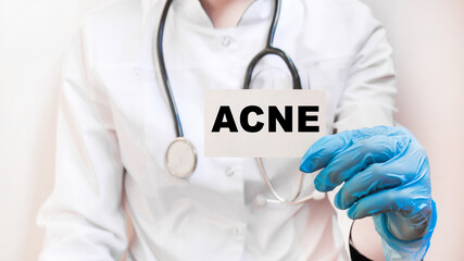 The doctor's blue - gloved hands show the word ACNE - . a gloved hand on a white background. Medical concept. the medicine