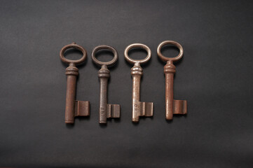 4 alte, leicht rostige Buntbartschlüssel in verschiedenen Ausführungen  vor einem schwarzen Hintergrund