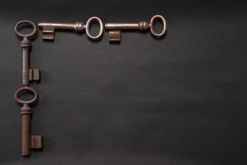 Vier alte, leicht rostige Buntbartschlüssel, angeordnet als Rahmen auf schwarzem Hintergrund