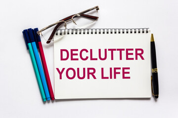 Declutter your life, text is written on a white notepad with stationery and a white background