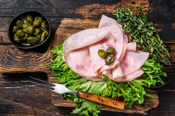 Sliced smoked ham with fresh salad and herbs. Dark wooden background. Top view