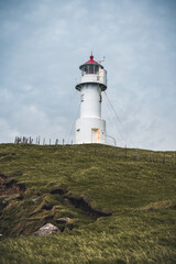 View Towards Lighthouse on the island of Mykines Holmur, Faroe Islandson a cloudy day with view towards Atlantic Ocean.