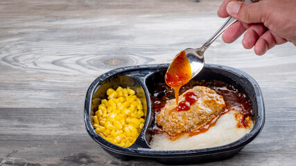 TV dinner and spooning gravy over the meat portion