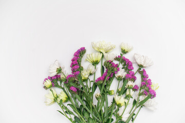 Pink statice and white chrysanthemum flowers on a white background. Top view. Copy space. Space for the text. The concept of the holiday.