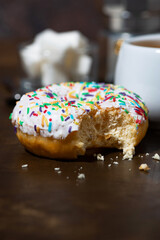 sweet donut with white frosting and a cup of black coffee, vertical closeup
