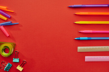Pens, rulers and paper clips, red background