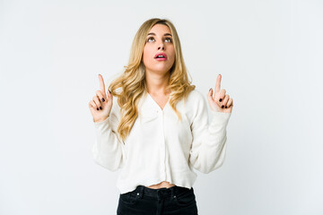 Young caucasian blonde woman pointing upside with opened mouth.