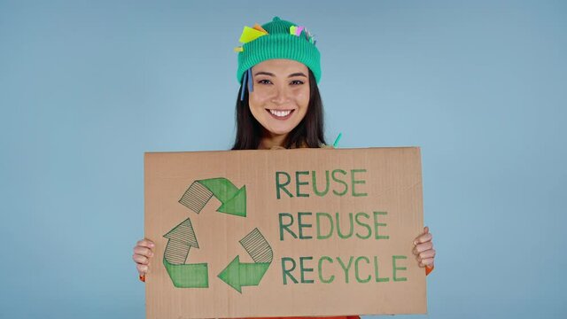Smiling asian woman holding cardboard with inscription reuse reduce recycle.