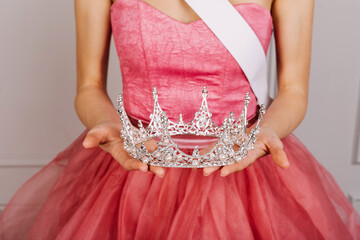 Closeup of a woman in tulle dress, holding a diamond crown. Beauty contest winner.