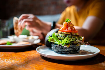 Broccoli quinoa charcoal burger topped with guacamole, mango salsa and fresh salad served on a...