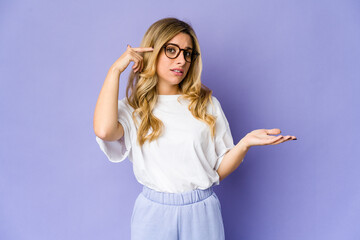 Young caucasian blonde woman showing a disappointment gesture with forefinger.