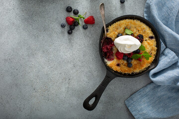 Berry crumble baked in small cast iron pans, individual desserts top view with whipped cream, copy...