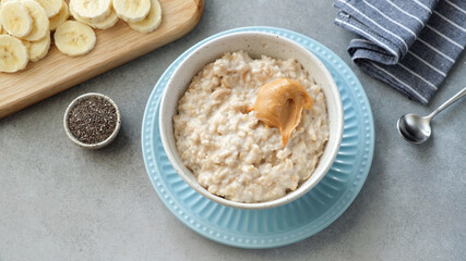 Oatmeal porridge with peanut butter and bananas served in a bowl. Top view. Healthy vegan breakfast...