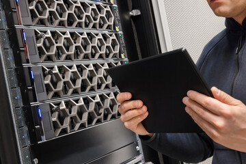 Male Computer Engineer With Digital Tablet Examining Hardware in Datacenter