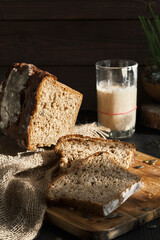 Fresh homemade leavened bread in the sun, partially sliced. Bread is located on a wooden surface. Hobbies, baking rye bread at sourdough at home. Healthy food concept, traditional craft bread. Closeup