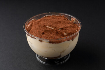 Tiramisu in a plastic delivery package on dark background for a menu
