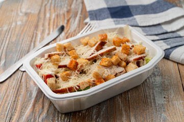 Pandemic food delivery: classic caesar salad with grated cheese and grilled chicken