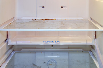 Dirty refrigerator shelves in the remains of old food, close up. Hygiene problems and cleaning of...