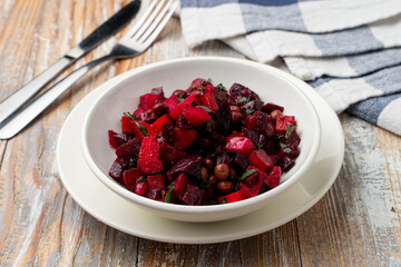 Ukrainian salad made of boiled vegetables in a white bowl on a rustic wooden table