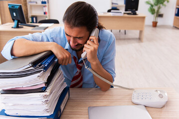 Young male employee unhappy with excessive work in the office