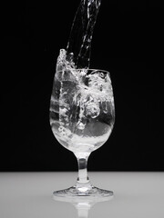 Glass with splashing water on black