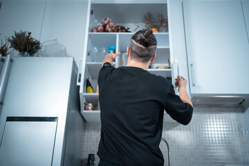 young attractive man open kitchen shelf with food to prepare eat at home
