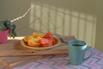 taza de cafe ,plato de frutas sobre tablas rústicas 