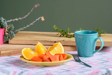 naranja y papaya en trozos con taza de cafe 
