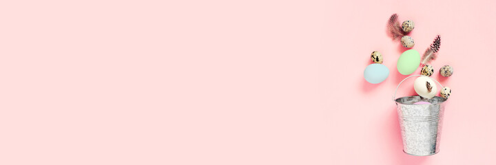 Festive banner with Easter eggs and feathers in the metal bucket on pink