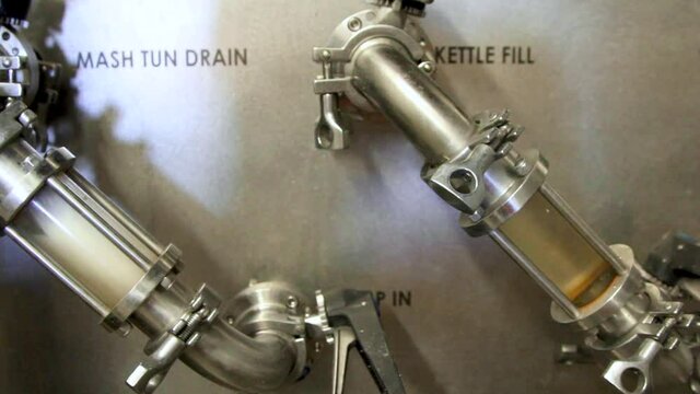 Close up shot showing fresh beer in kettle tank producing in beer factory. Checking the color of liquid.