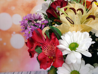 Bouquet of flowers varied in a glass vase on a background of sparkles and a wooden base