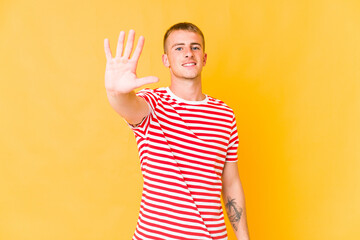 Young caucasian handsome man smiling cheerful showing number five with fingers.