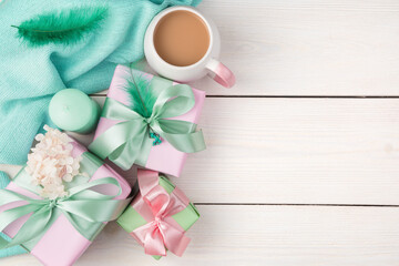 Gifts, candles, coffee and a sweater on a white wooden background. Top view, with space to copy. The concept of festive backgrounds, March 8.