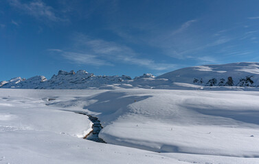 sunny winter day in the Swiss alps with a sunstar, blue sky and idyllic winter landscape in Melchsee-Frutt