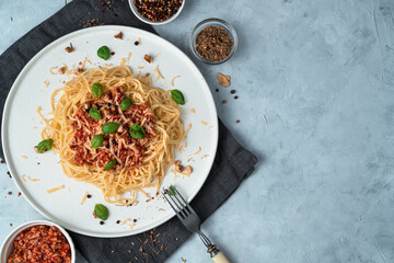 Pasta with sauce on a flat white plate on a gray background. The view from the top. The concept of culinary backgrounds.