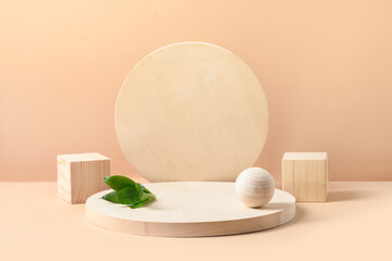 Fototapeta na wymiar Stands for product of wooden natural shapes. Cube, ball and plate as podium. Creative composition with green leaf on beige background.