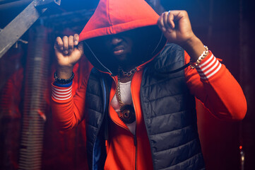 Rapper in red hoodie poses in grunge studio - obrazy, fototapety, plakaty