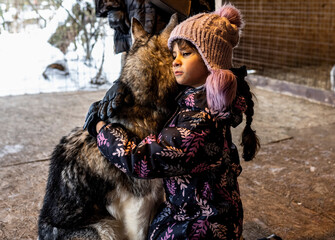 beautiful girl in a purple hat plays with big dogs Husky in an aviary