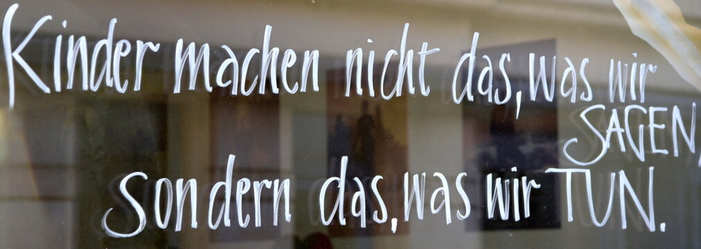 Schrift auf einer Glasscheibe: "Kinder machen nicht das, was wir sagen, sondern das, was wir tun."