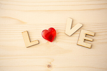 Wooden letters with the inscription of the word "Love" on a wooden background and with a red heart