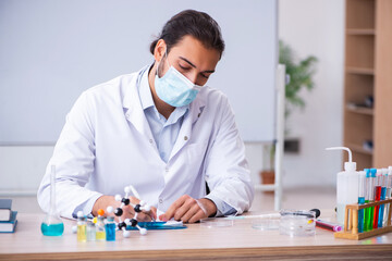 Young male chemist teacher sitting in the classroom