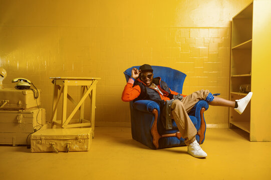 Rapper Posing In Chair In Studio With Yellow Tones