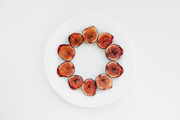 Ripe and sweet figs cut and arranged in a plate on a white background with free space. Fruits and vegetarianism